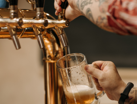 Man with tattoos getting pours draft beer off the tap