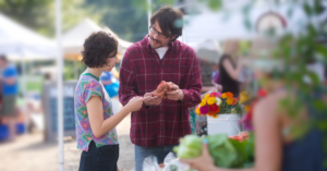 A couple holding products while discussing them at a farmer's market