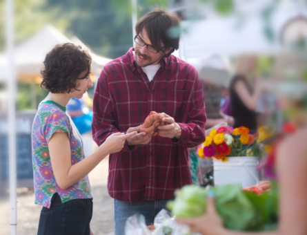 A couple holding products while discussing them at a farmer's market